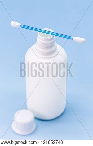 Hydrogen Peroxide, In White Plastic Bottle, With Cotton Swab And Isolated Blue Background, Medicine 