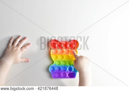 Children's Hands Play With The Rainbow Pop It Fidget Toy. Touch Toy Is A Reusable Silicone Stress Re