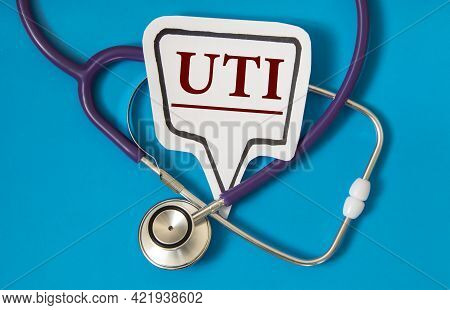 Uti - Acronym On White Figure Sheet On A Blue Background With A Stethoscope. Medical Concept