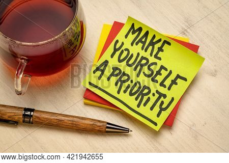 Make yourself a priority advice or reminder - handwriting on a sticky note with a cup of tea, self care and personal development concept