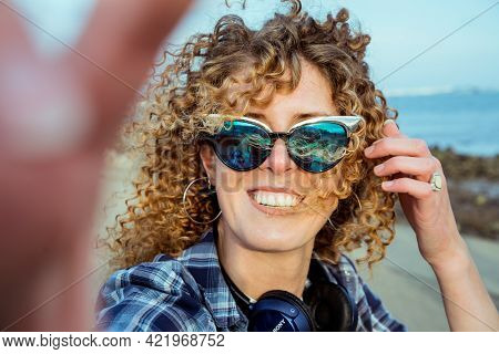 Close-up Curly Hair Woman In Sunglasses Making Selfie Photo On Camera. A Pretty Young Female With He