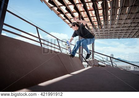 Skateboarder Jumping High On Mini Ramp At Skate Park Outdoor.