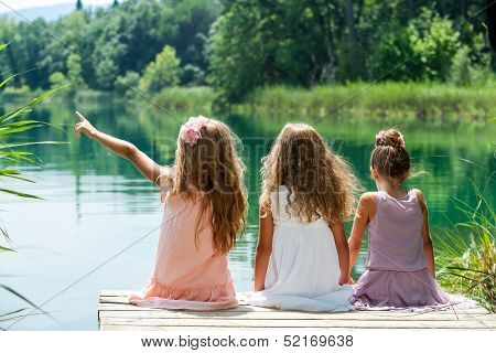 Three Girl Friends Together On River Jetty.