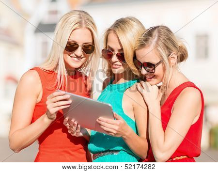 holidays and tourism concept - beautiful blonde girls toursits looking into tablet pc in the city