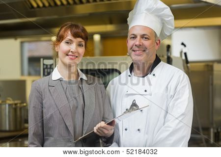 Mature head cook posing with the female manager in a professional kitchen