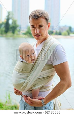 Father carrying his son in sling
