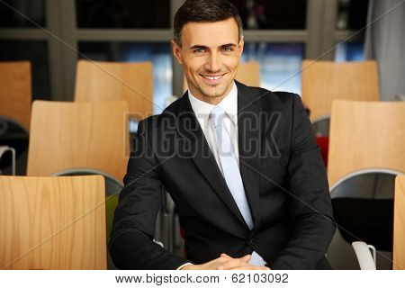 Cheerful businessman sitting at conference hall