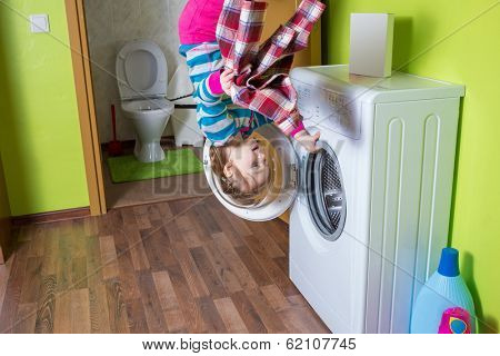 Girl with shirt upside down holding a washing machine at inverted house