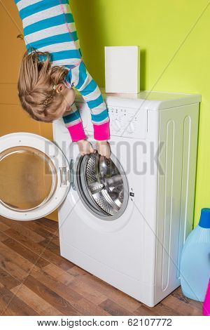 Girl hanging upside down holding a washing machine at inverted house
