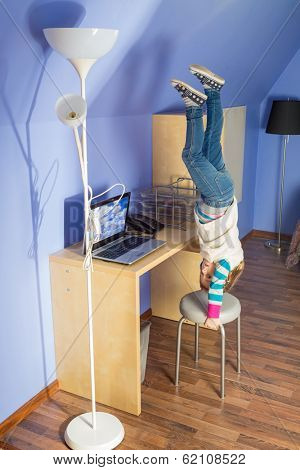 Little girl in jeans upside down on the chair at inverted house