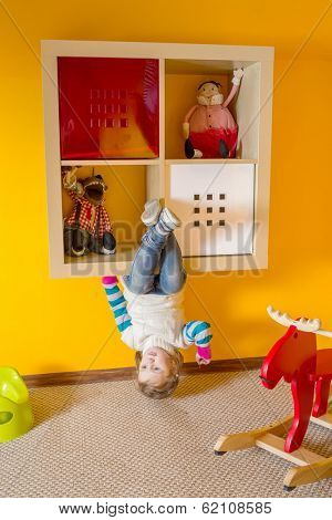 Little girl in children room sitting upside down at inverted house