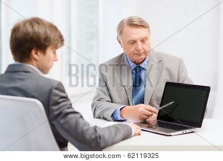 business, advertisement, technology and office concept - older man and young man with laptop computer in office