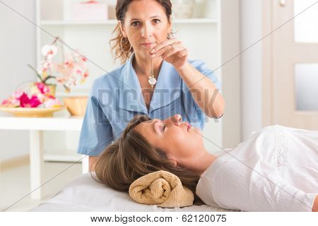 Alternative medicine therapist using pendulum to make a diagnosis