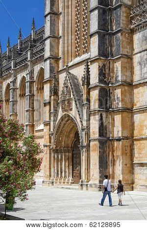 Batalha, Portugal - July 17, 2013: Locals passing by the South Portal of the Batalha Monastery. Masterpiece of the Gothic and Manueline. UNESCO World Heritage Site.
