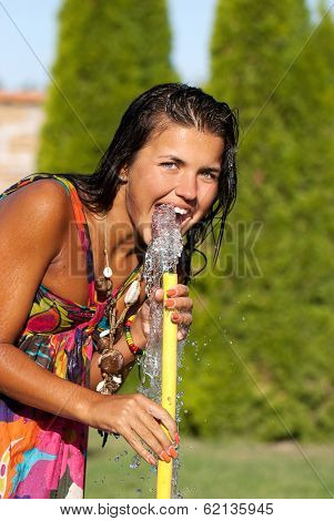 The young girl drinking water from a hose