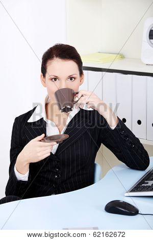 Young beautiful business woman is having break with cup of coffee or tea.