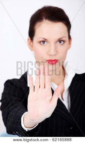 Beautiful business woman is keeping her hand ahead, making stop sign.