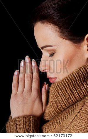 Young woman praying. Over black background.