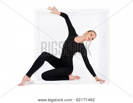 Modern bellet dancer posing with a cube at studio. Plastic body concept. Isolated over white.