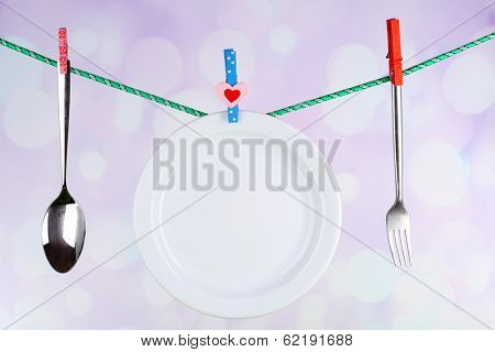 Tableware dried on rope on bright background