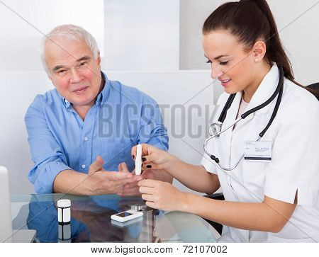 Doctor Using Lancelet On Senior Man