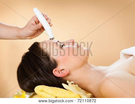 Woman Receiving Microdermabrasion Therapy On Forehead At Spa