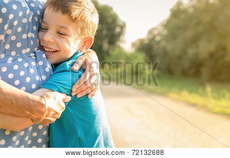 Happy grandson hugging to his grandmother outdoors