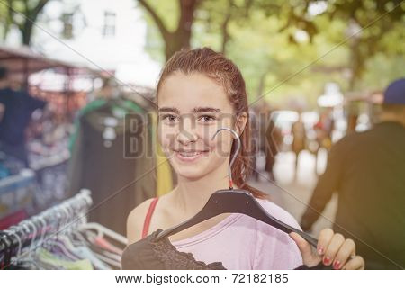 Smiling Woman On A Flea Market Is Holding A Clothes Hanger