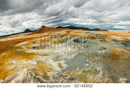 Mudpot in the geothermal area Hverir, Iceland. The area around the boiling mud is multicolored and cracked. 