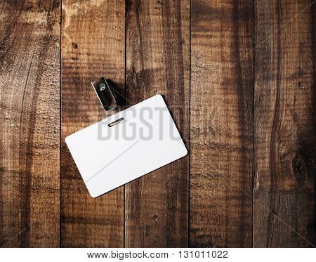 Blank badge. Blank plastic id card on vintage wooden table background. Blank white plastic badge. Mock-up for branding identity. Top view.