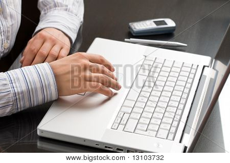 Hands working on a laptop computer, overhead view.
