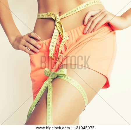 woman measuring waist with tape on knot like a gift, tann isolated close up white background good feat for summer