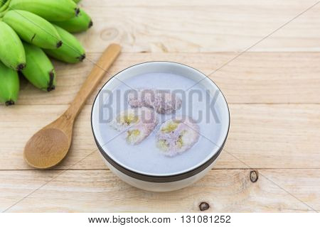 Banana in coconut milk (Kluay Buad Chee) on wood desk Thai desert.