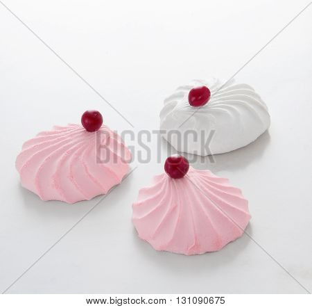 Three marshmallow on a table decorated with cranberries