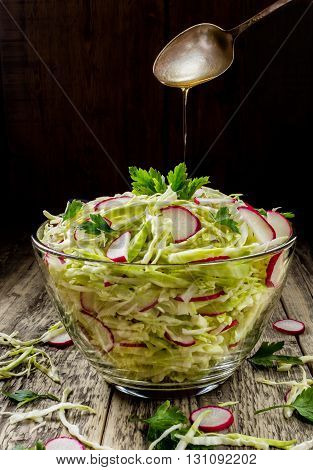 Fresh vegetable salad from chopped cabbage and radish roses. On a dark background of old boards