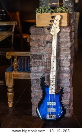 Bass Guitar Leaning Against Brick Wall. Blue Bass Guitar. Still Life with Bass Guitar.