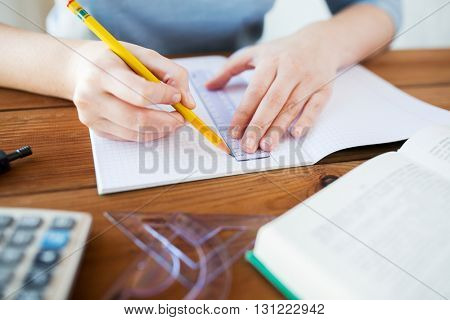 school, education, people and learning concept - close up of student or woman hands with ruler and pencil drawing line in notebook