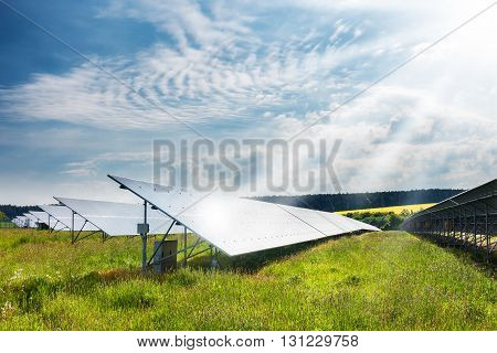 Landscape with solar power plant. Solar panels in sunny summer countryside under sun rays and blue sky. Solar power generation. Czech Republic Europe