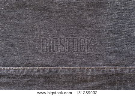 denim or rough cotton fabric or jeans material with the stitched seam for the textile textured background of dark color