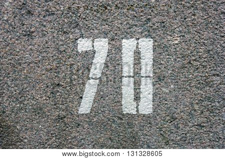 sign figure number seventy painted by white paint stencil on red granite stone surface