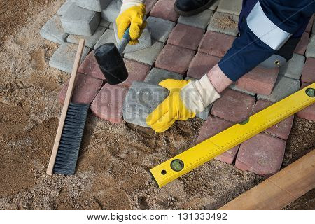 mason worker making sidewalk pavement with stone blocks
