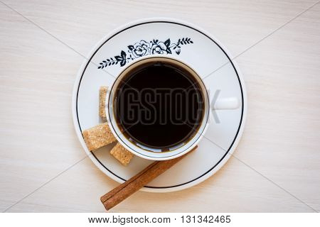 Cup of coffee on a plate with brown sugar and cinnamon stick