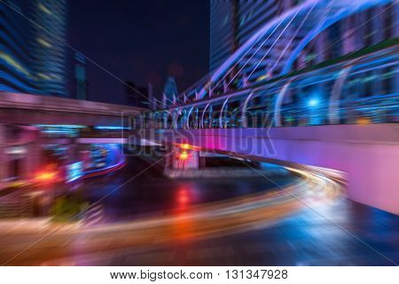 Light trails from the vehicles at the intersection with a walk-over pedestrain bridge