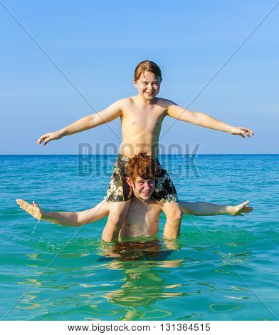 Brothers Enjoying The Clear Warm Water And Play Piggyback