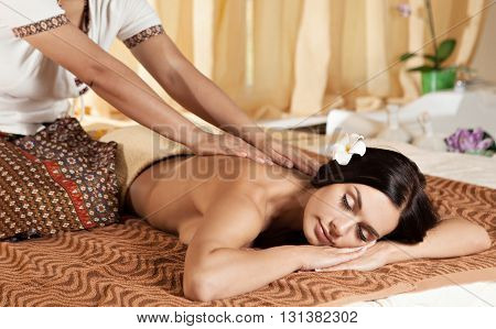 Thai massagist doing massage for european woman in spa salon