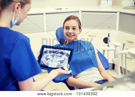 people, medicine, stomatology, technology and health care concept - happy female dentist with teeth x-ray on tablet pc computer and patient girl at dental clinic office