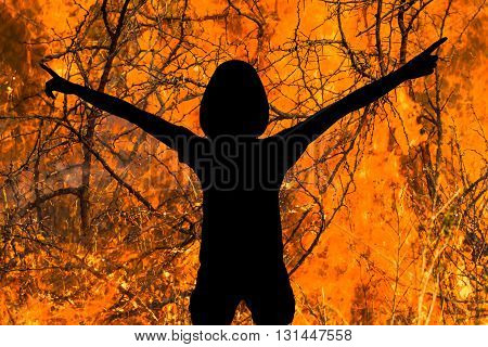 Silhouette of woman with arms raised in the flames. Concept of danger, of strength, of courage, of heroism, of devil.