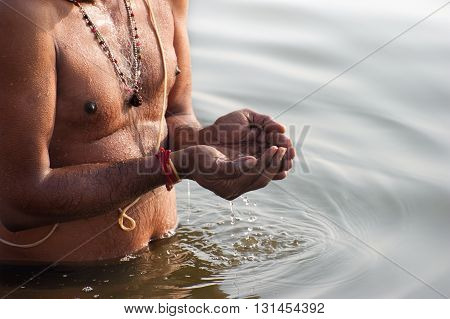 Prayer hands pouring sacred water to the river during the daily worship