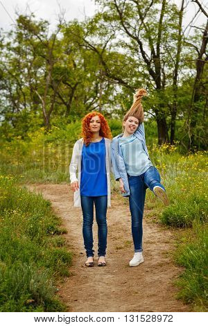 Best friends forever. Girlfriends standing on a footpath in the park. BFF. Close friends. Gentle friendship. Girl holding her hair