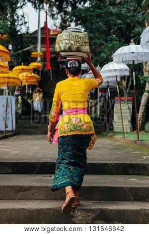 UBUD INDONESIA - MARCH 02: Balinese woman in traditional clothes carrying ceremonial box with offerings on her head during Balinese New Year or Nyepi Day celebrations on March 03 2016 in Ubud Bali.
